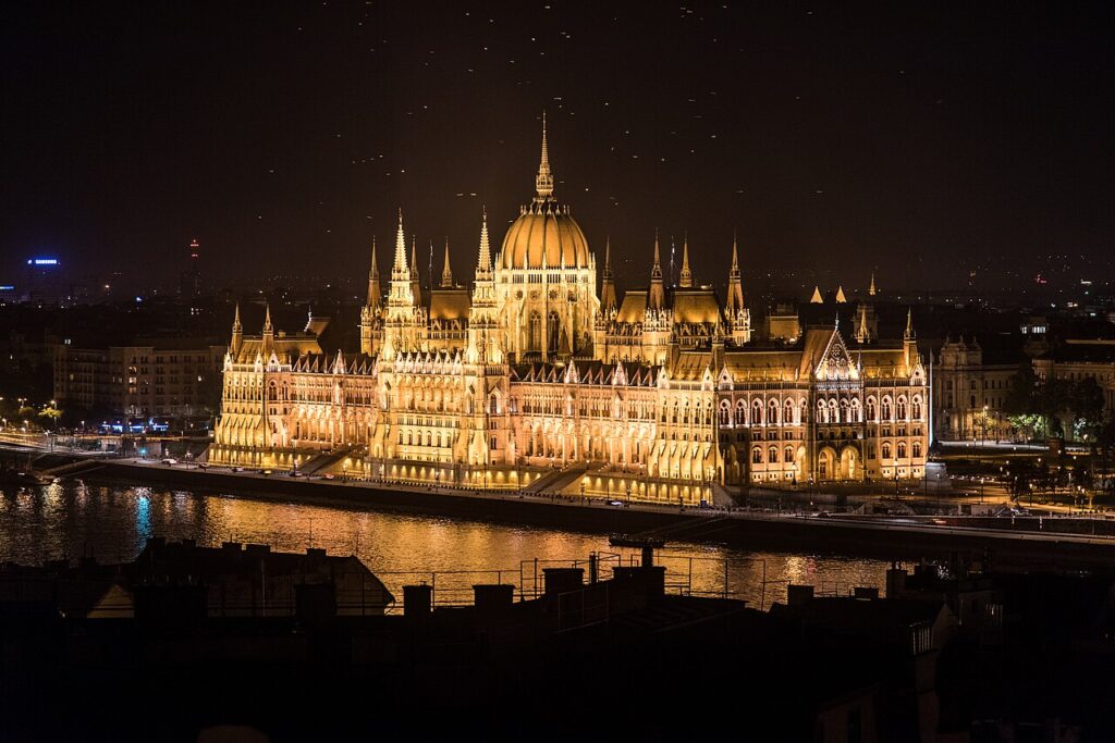 Budova maďarského parlamentu v Budapešti pri Dunaji v nočnom osvetlení